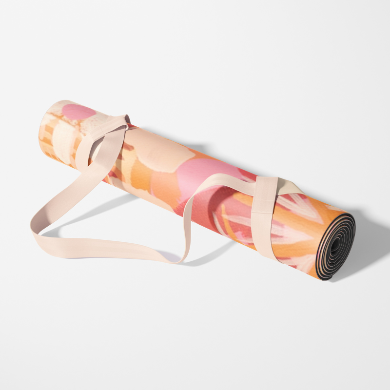 The Indie yoga mat rolled up neatly, showcasing its compact, eco-friendly design and vibrant artistic pattern in warm orange, pink, and yellow tones, made with sustainable materials for easy portability.